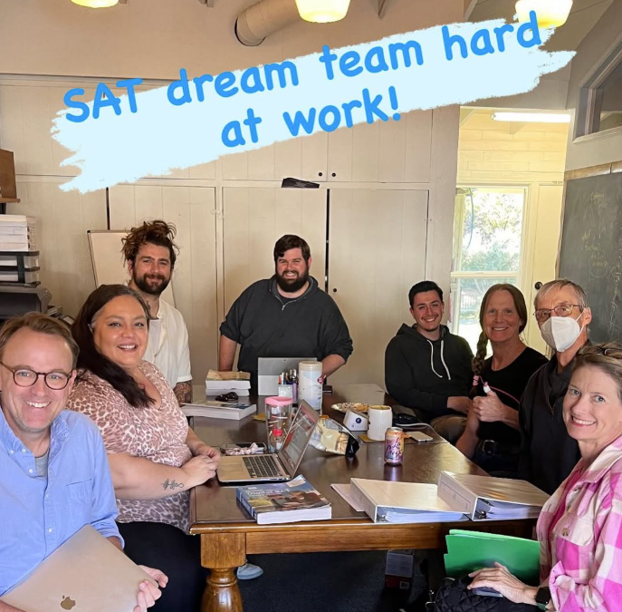 Group picture of several Stepping Stones staff members sitting at a meeting table preparing for SAT programming