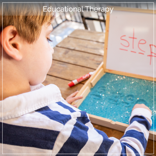 Young boy writing letters in sand on a table