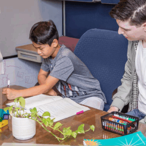 Male tutor with pre-teen boy studying at a table together